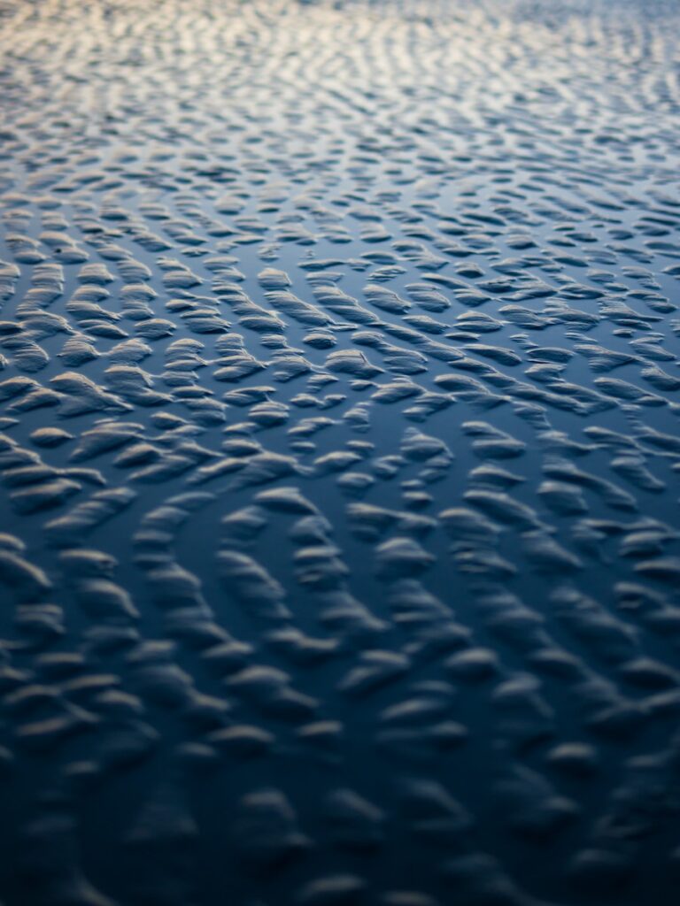 a beach covered in waves and clouds at sunset